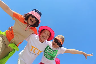 Three happy Asian women jumping against blue sky