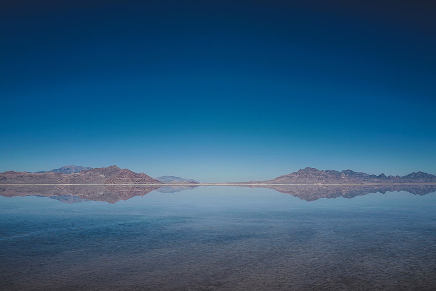 Serene desert lake reflecting mountains under clear blue sky
