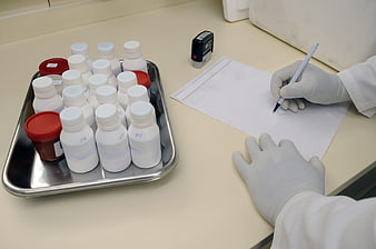 Lab Technician Recording Data with Chemical Bottles