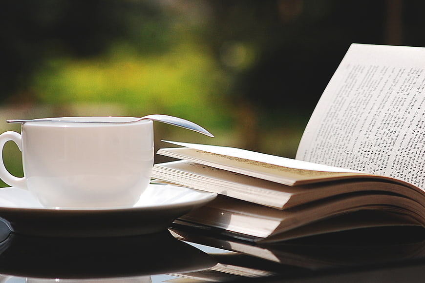 White Coffee Cup and Open Book on Table