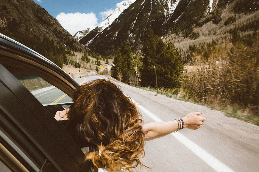 Woman leaning out of car window on mountain road