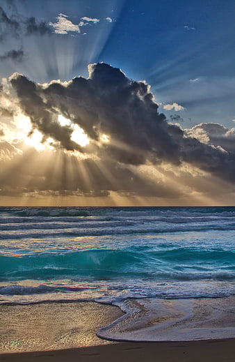 Dramatic Sun Rays Breaking Through Clouds Over Turquoise Ocean Waves
