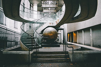 Modern concrete spiral staircase with golden sphere sculpture