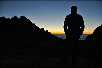 Silhouette of Man Standing on Cliff at Sunset
