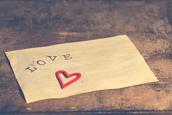 Vintage paper with love text and red heart on rustic wood