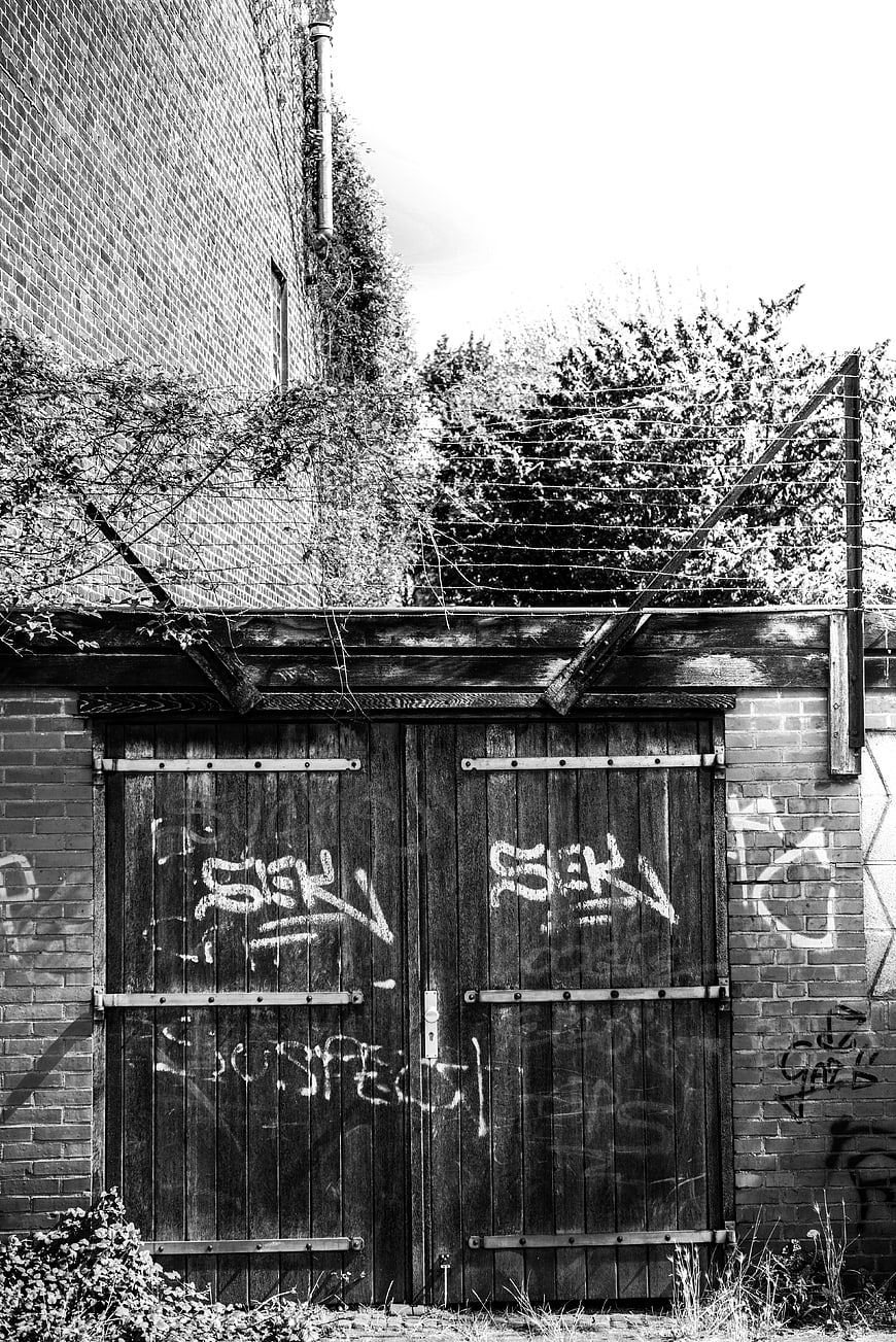 Black and white photo of graffiti-covered wooden gate