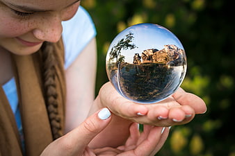 Girl holding crystal ball with landscape reflection