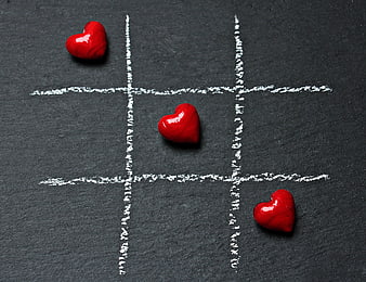 Red hearts winning tic-tac-toe game on black slate