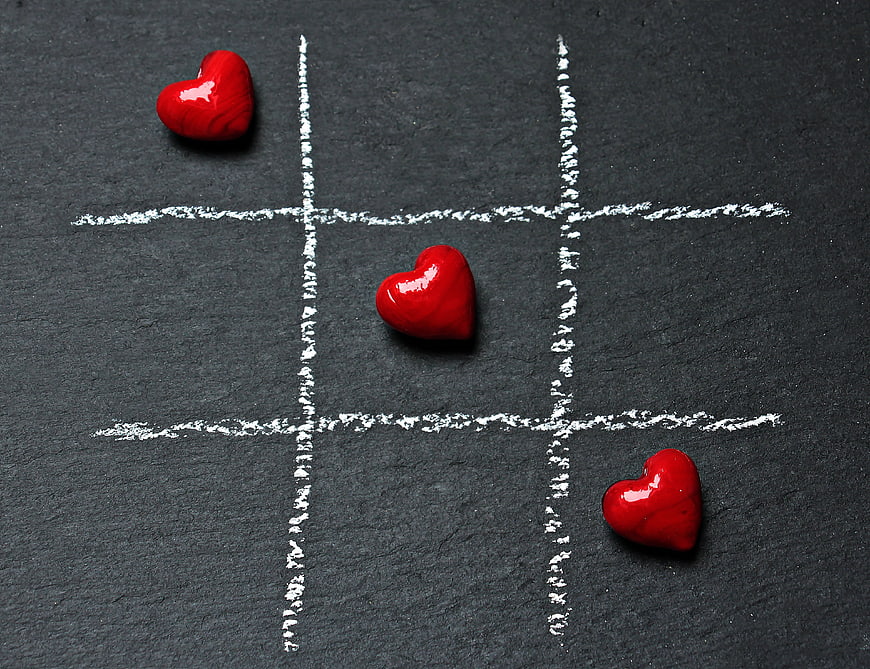 Red hearts winning tic-tac-toe game on black slate