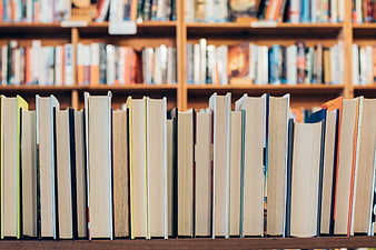 Close-up of books on a wooden library shelf