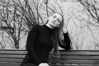 Black and white portrait of woman sitting on park bench
