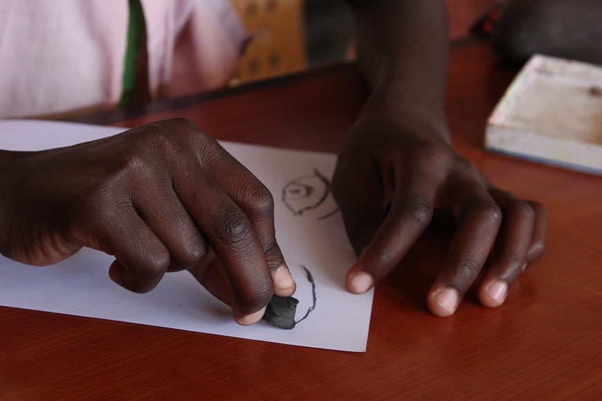 Close-up of child drawing with charcoal on paper