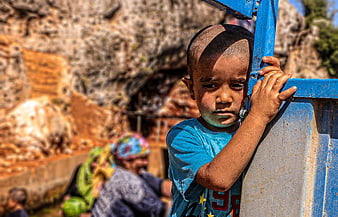 Portrait of young boy holding blue metal structure outdoors