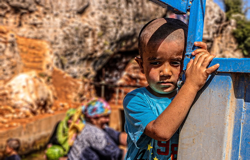 Portrait of young boy holding blue metal structure outdoors