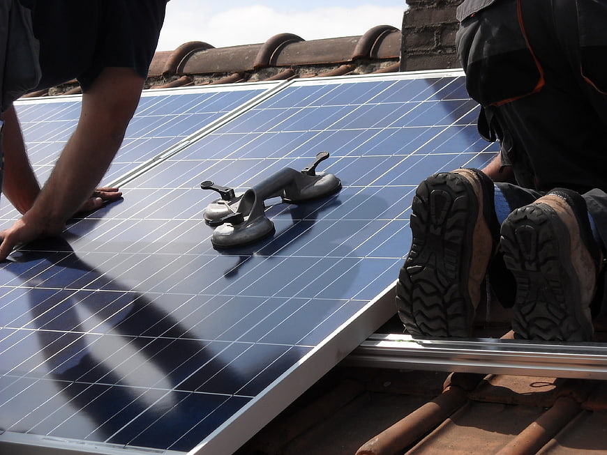 Workers installing solar panels on a tiled roof