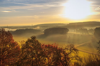 Misty Autumn Sunrise Over Rolling Hills And Forest