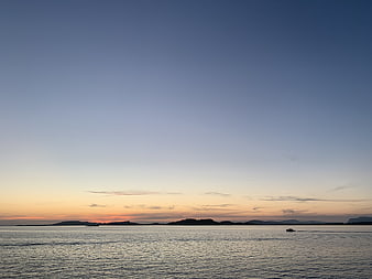 Serene Sunset Over Calm Ocean with Distant Islands