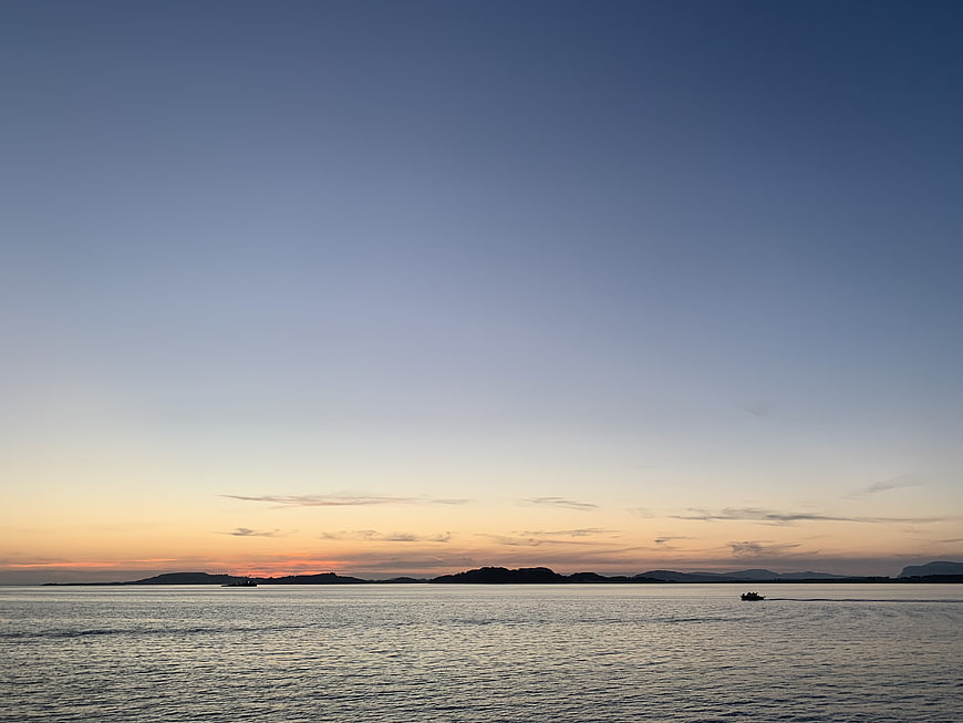 Serene Sunset Over Calm Ocean with Distant Islands