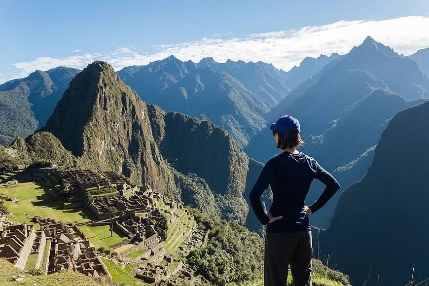Woman overlooking Machu Picchu ruins and mountains