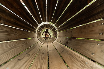 Child climbing through wooden tunnel playground structure