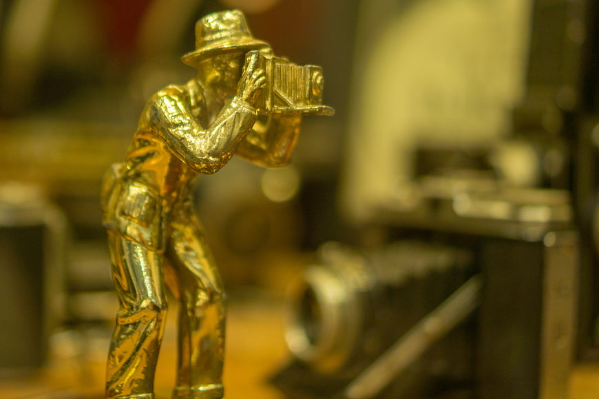 Golden vintage photographer figurine with antique camera