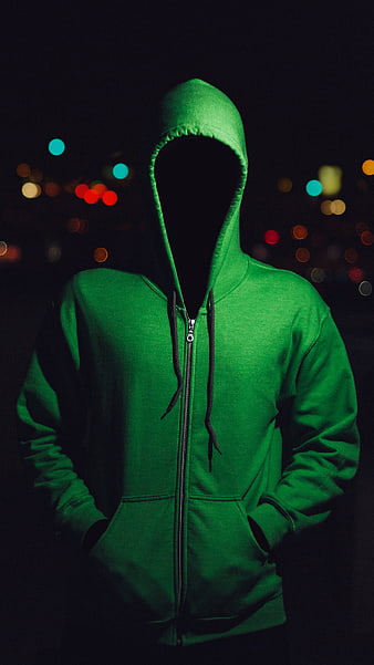 Anonymous figure in green hoodie with faceless hood at night