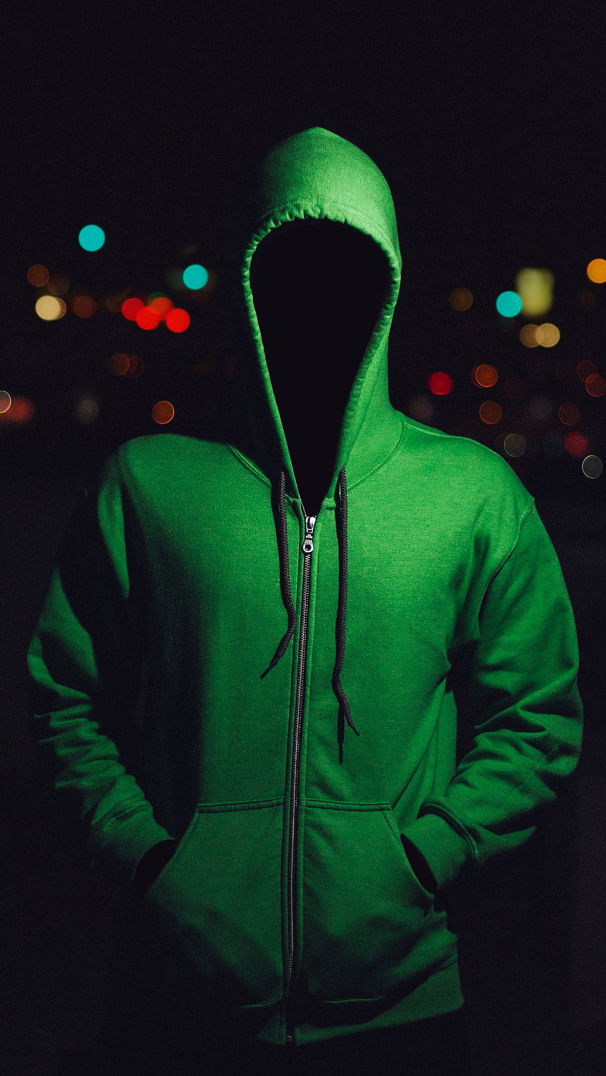 Anonymous figure in green hoodie with faceless hood at night