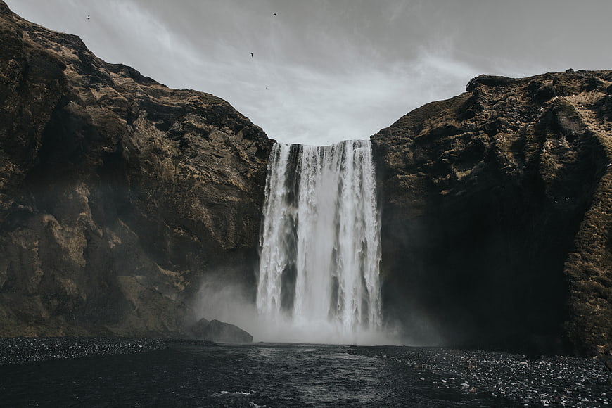 Majestic waterfall cascading into a misty river canyon