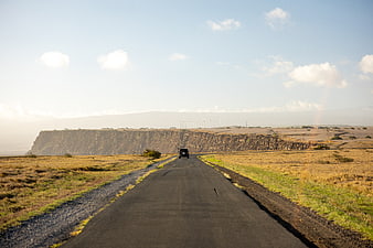 Jeep driving on rural road with cliffs and wind turbines