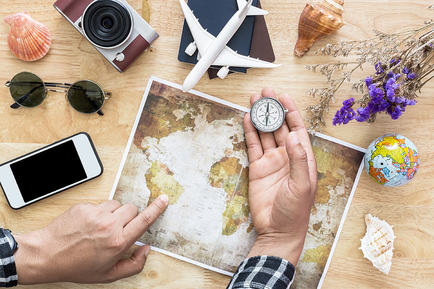 Travel planning concept with map, compass, and accessories on wooden table