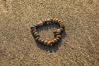 Heart shape made of pebbles on sandy beach