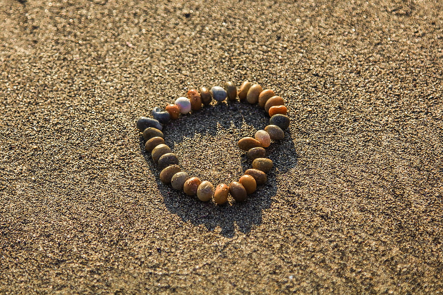 Heart shape made of pebbles on sandy beach