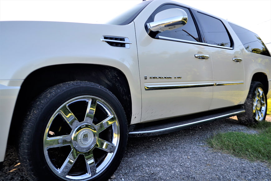 Side view of white Cadillac Escalade ESV with chrome wheels