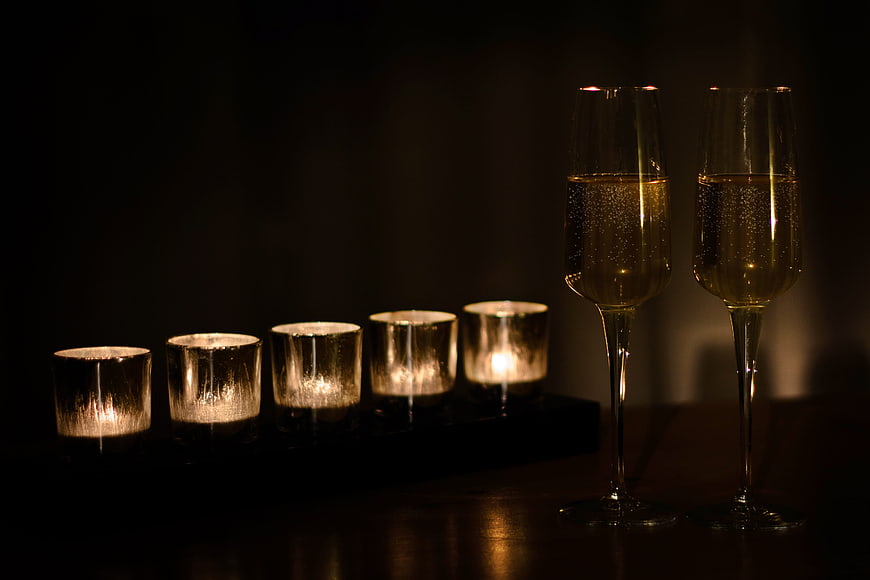 Two Champagne Glasses and Candles in Dark Romantic Setting