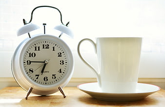 White Alarm Clock and Coffee Cup on Wooden Table