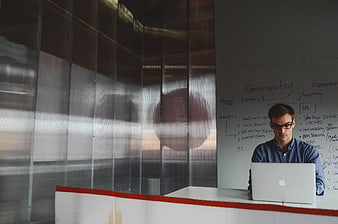 Young entrepreneur working on laptop in modern office with whiteboard