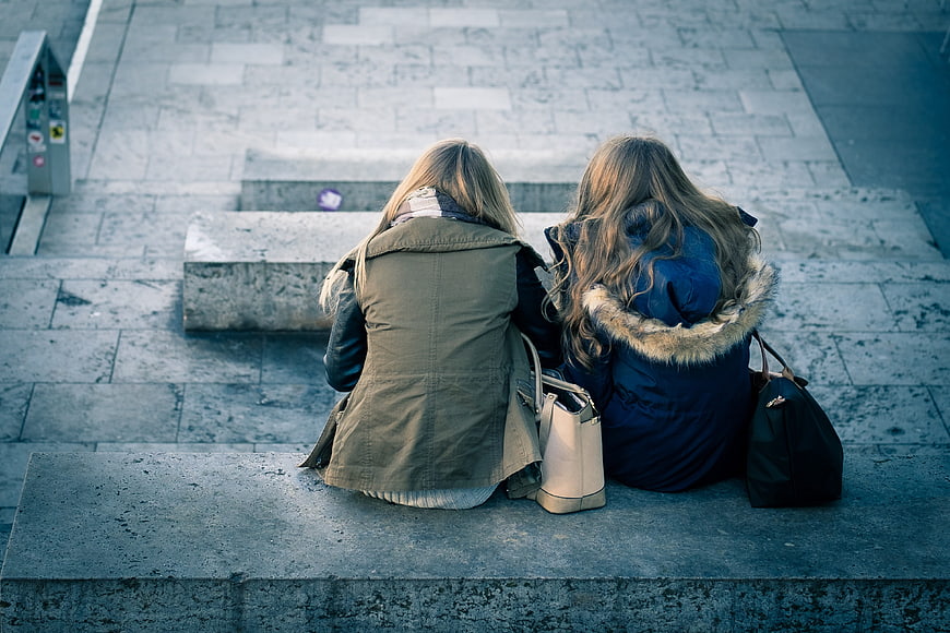 Two women sitting on stone steps from behind