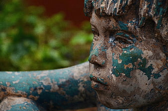 Close-up profile of a weathered bronze statue of a young boy