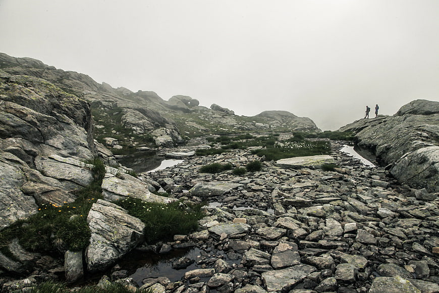 Hikers on Rocky Mountain Ridge in Foggy Weather