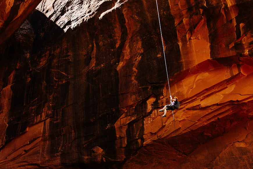 Rappelling down a massive red rock canyon wall