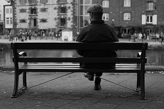 Man in Flat Cap Sitting on Riverside Bench