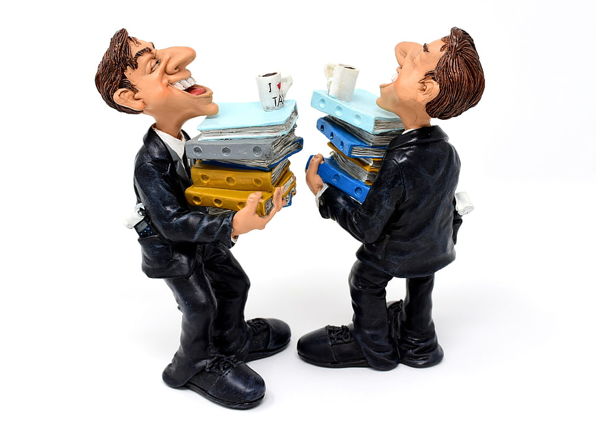Two Funny Businessman Figurines Carrying Stacks of Tax Files