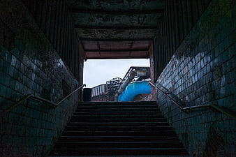 Dark industrial stairs leading to blue pipe structure