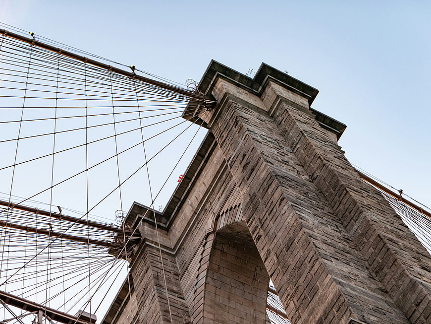 Low angle view of Brooklyn Bridge stone tower and cables