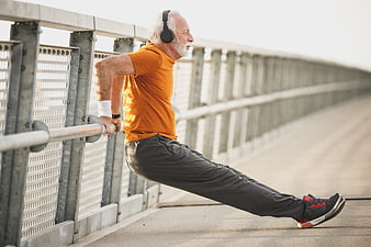 Senior man doing tricep dips on bridge railing