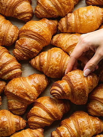 Hand Picking Golden Flaky Croissants from Bakery Tray
