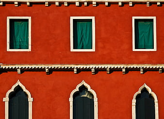 Red Venetian building facade with green curtains and arched windows