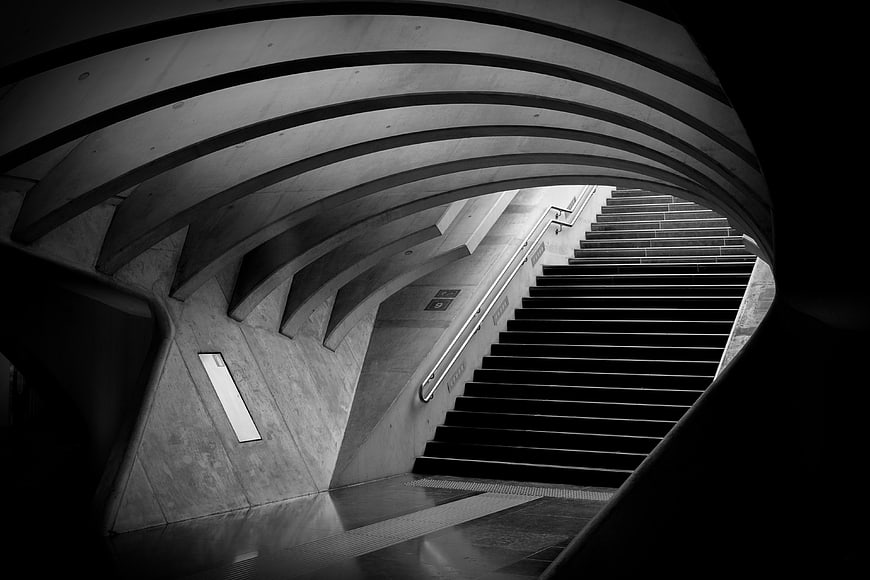 Black and white architectural photo of curved concrete subway stairs