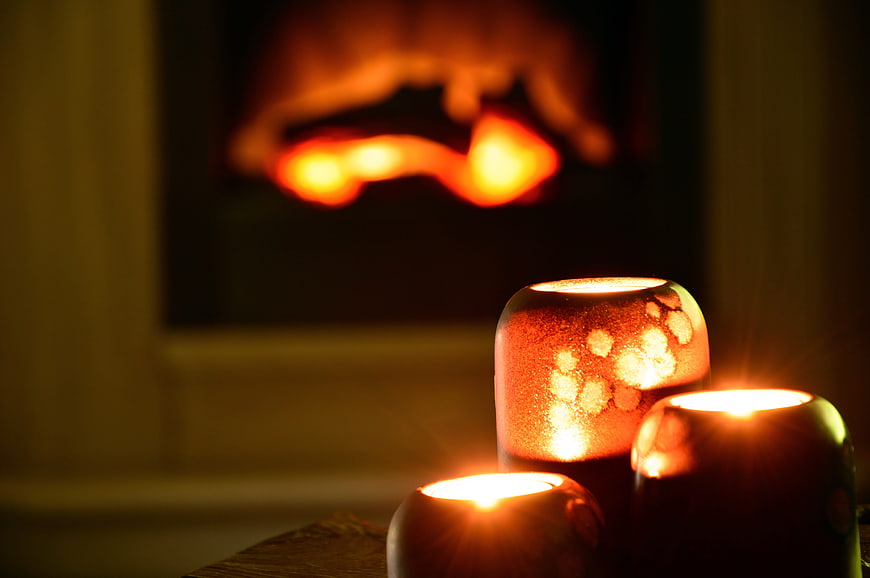 Cozy Lit Candles In Front Of A Warm Glowing Fireplace