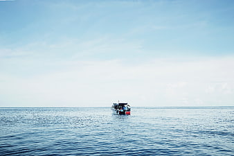 Small boat sailing on calm blue ocean horizon
